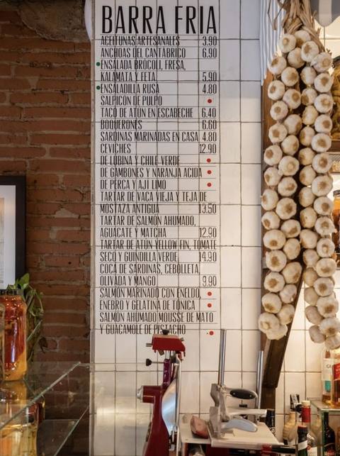 Pizarra con la carta de una barra fría y ristras de ajos colgadas